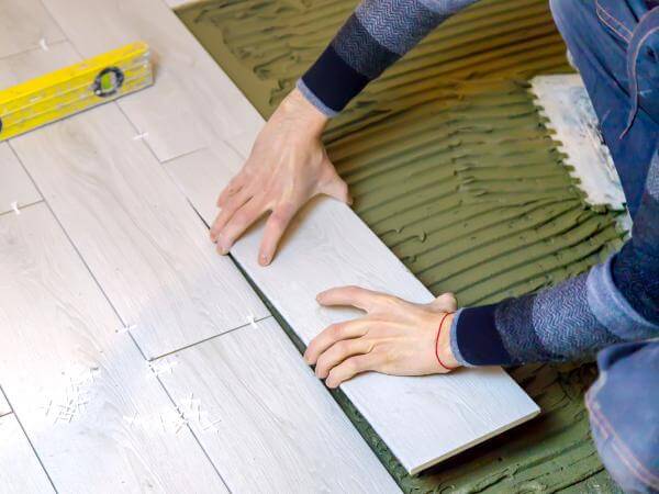 Vue en contre-plongée d'un artisan carreleur posant du carrelage à Quimper.